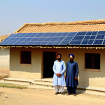 Solar Power in Rural Punjab**

"A vibrant, sunny scene in a rural Punjabi village, Pakistan. A family, fully clothed in traditional shalwar kameez, stands proudly in front of their home. Solar panels are installed on the roof, providing clean energy. Safe for work, appropriate content, professional photography, family-friendly, perfect anatomy, natural proportions, high resolution."

**