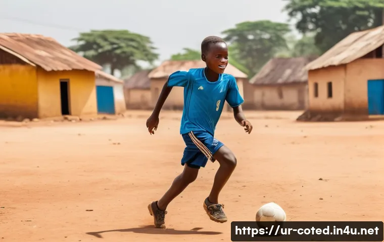 코트디부아르 야야 투레 커리어 - A young African boy wearing a football jersey and shorts, playing soccer passionately on a dusty vil...
